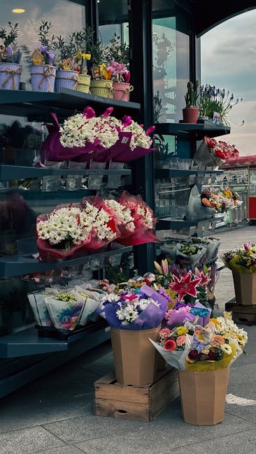An outdoor display of floral arrangements and bouquets at hornchurchflorist.org.uk, featuring various fresh flowers including white daisies, pink lilies, and purple statice, wrapped in colored paper a